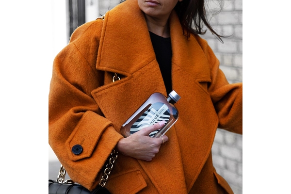 Image A woman holding a water bottle in her hand while walking.